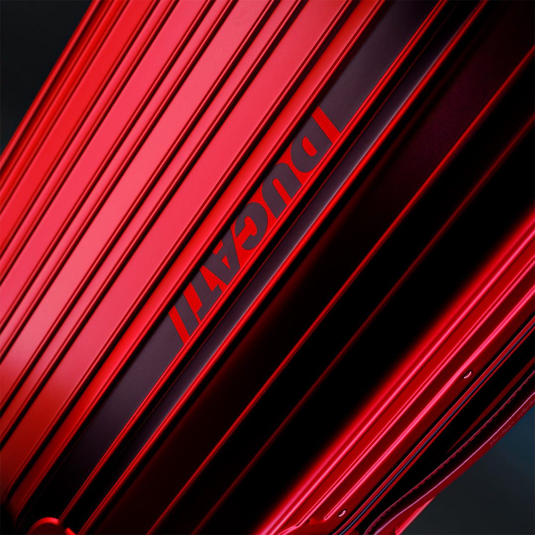 Close-up of a red hard-shell luggage surface with parallel ridges and the word ‘DUCATI’ printed along a central strip.